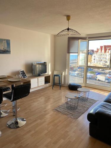 un salon avec un canapé et une télévision dans l'établissement Les Rameaux, superbe appartement vue mer, Wimereux, à Wimereux