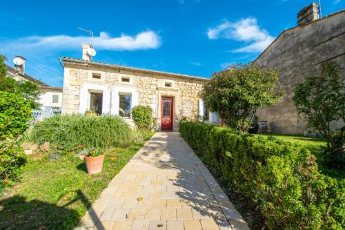 una casa de piedra con una puerta roja en un patio en Ô FIL DE L ISLE, en Savignac-sur-lʼIsle