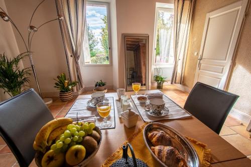 una mesa con un bol de fruta y dos vasos de zumo de naranja en Ô FIL DE L ISLE, en Savignac-sur-lʼIsle