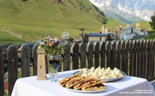 una mesa con dos platos de galletas y una copa de vino en Hotel-Cafe Koshki Ushguli, en Ushguli