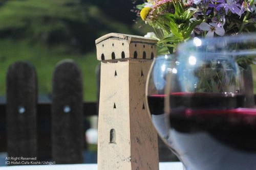 Una botella de vino sentada junto a un jarrón de flores. en Hotel-Cafe Koshki Ushguli, en Ushguli