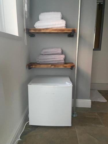 una pequeña nevera blanca en un armario con toallas en Adorable bedsit for you, partner and your pet! en Pembrokeshire