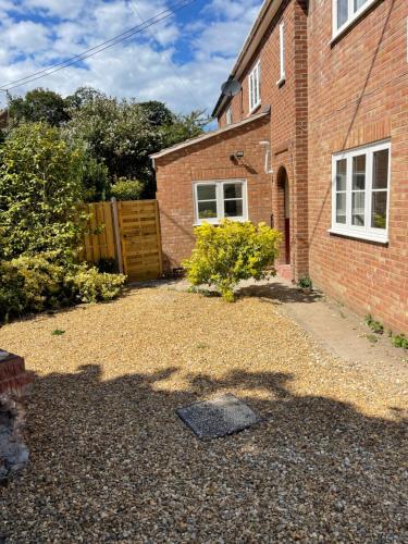 a backyard of a brick house with a driveway at Fisherman's Retreat in Wells next the Sea