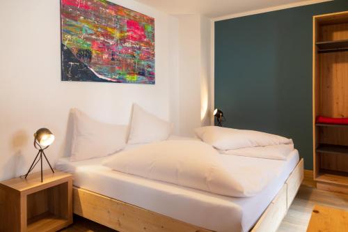 a bedroom with a white bed with a painting on the wall at Sаfestay Kitzbühel Alpine in Kitzbühel