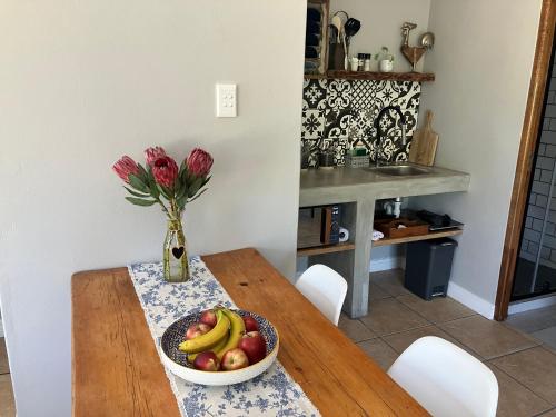 a table with a bowl of fruit and a vase of flowers at UpperRoom Ceres -Indoor Braai in Ceres