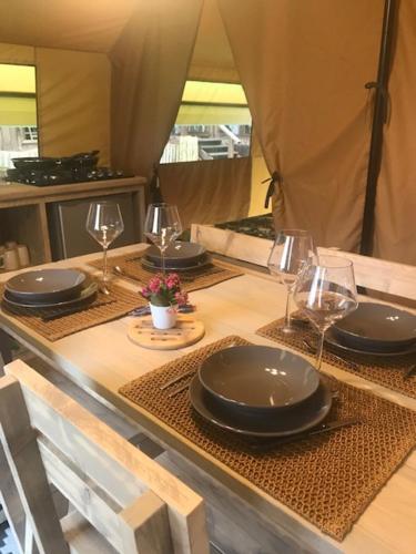 une table avec des assiettes et des verres à vin dessus dans l'établissement Oh! Campings - L'Espiguette, au Grau-du-Roi