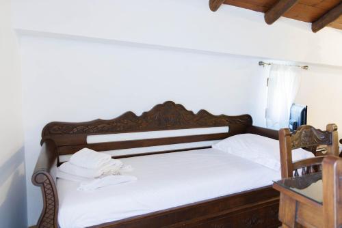 a bedroom with a wooden bed with white sheets at Castello di Haria in Kaloú