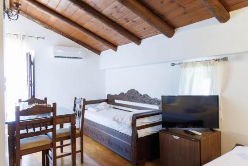 a bedroom with a bed and a desk and a tv at Castello di Haria in Kaloú