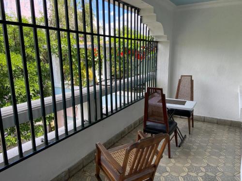 a balcony with two chairs and a table and a window at Hostal Cumbres del Volcan Flor Blanca in San Salvador