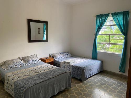 two beds in a room with a mirror and a window at Hostal Cumbres del Volcan Flor Blanca in San Salvador
