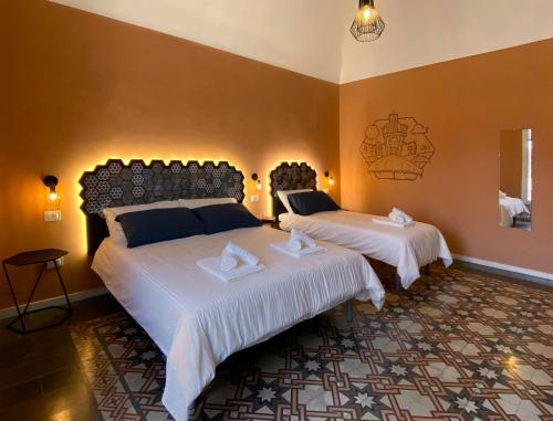 um quarto com 2 camas com edredões brancos em Liotru Maisonne em Catânia
