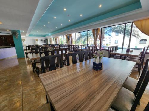 un restaurante con mesas y sillas de madera y ventanas en Aquavista Hotel & Suites, en Áqaba