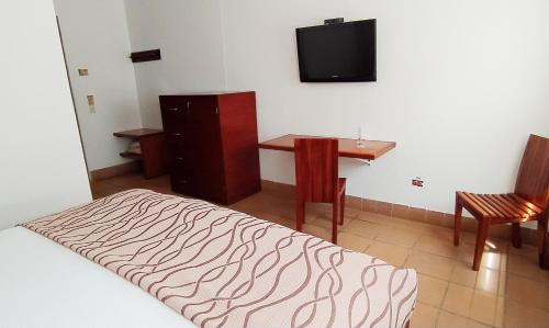 a bedroom with a bed and a desk and a television at Hotel Xue Sabana in Cajicá