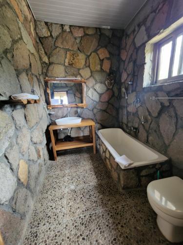 a stone bathroom with a tub and a sink at Sora Lodge Lalibela in Lalībela