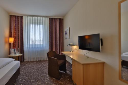 a hotel room with a bed and a desk with a television at Hotel Lenz in Fulda