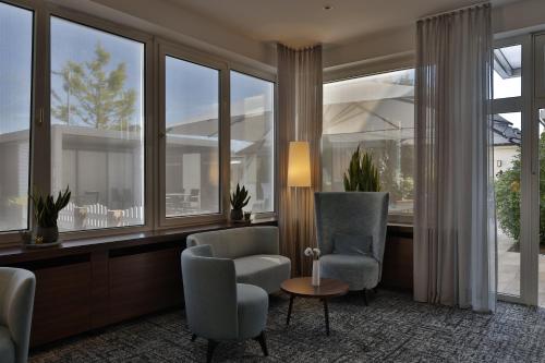 - un salon avec deux chaises, une table et de grandes fenêtres dans l'établissement City Partner Hotel Lenz, à Fulde