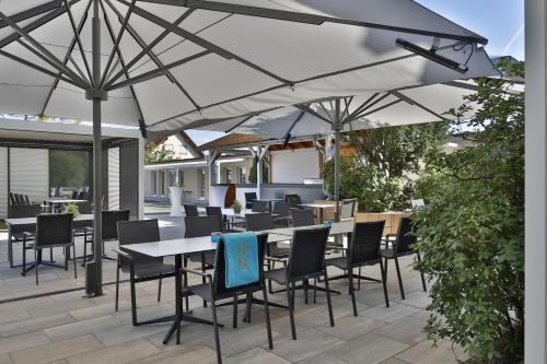 a patio with tables and chairs under an umbrella at Hotel Lenz in Fulda