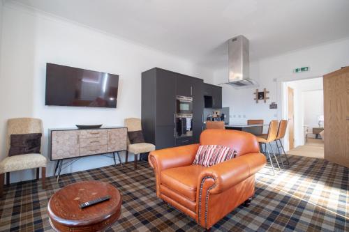 Una sala de estar con una silla naranja y una cocina. en Gordonston Apartments, en Inverness