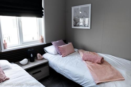 a bedroom with two beds and two windows at Holiday Lodge 6 in Porthcawl