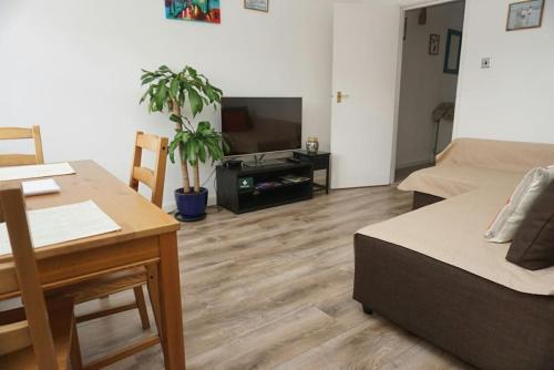 a living room with a bed and a table and a tv at Lovely & bright 1 bedroom apartment near the beach in Brighton & Hove