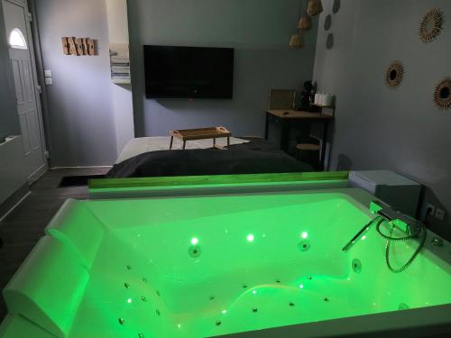 eine grüne Badewanne in einem Schlafzimmer mit einem Bett in der Unterkunft Chambre privative avec baignoire balneo in Crespin