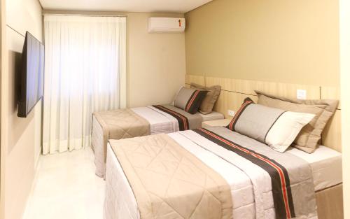 a hotel room with two beds and a television at Apartamento completo - Vila A in Foz do Iguaçu