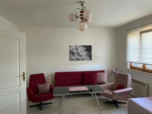 a living room with a red couch and two chairs at Srní- Červený byt/ dvojdomek u hotelu Vydra in Srní