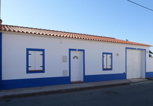 a white building with three doors on a street at A Janela do Alentejo in Campinho