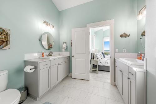 a white bathroom with two sinks and a toilet at Alta Vista in Pacific City