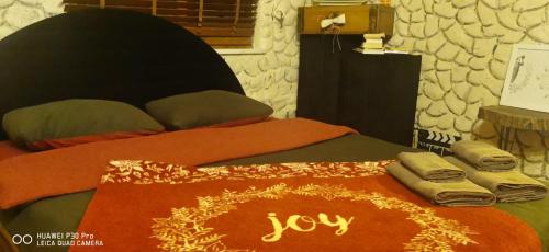 a bed with a comforter with the word joy on it at Into the wild in Tayakadın