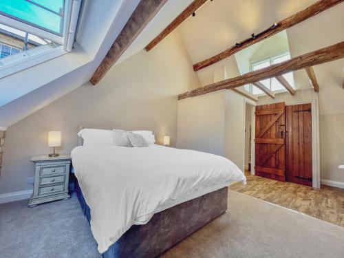 Un dormitorio con una cama grande y una ventana en Grooms Lodge, Chipping Campden - Taswell Retreats, en Chipping Campden