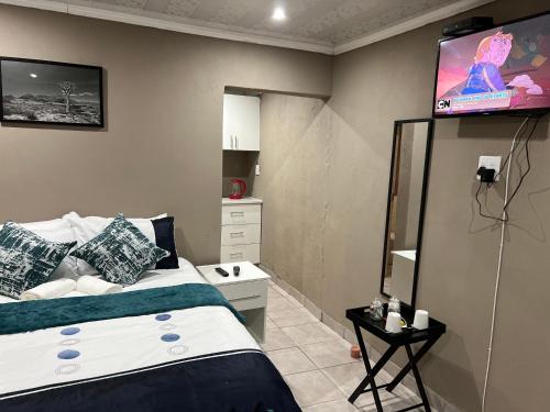 - une chambre avec un lit et une télévision murale dans l'établissement Ekhenani Guest House, à Nongoma