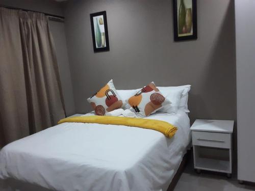 a bedroom with a bed with three pillows on it at Ekhenani Guest House in Nongoma