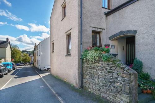 a building with a stone wall next to a street at Ground Floor 1 Bed Apartment with Twin/King option in Broughton in Furness