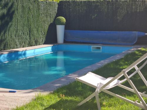 une chaise blanche assise à côté d'une piscine bleue dans l'établissement Chalet Aldeamayor Golf VUT 47-269, à El Cardiel