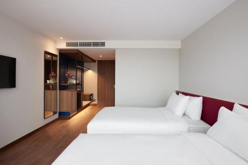two beds in a hotel room with a tv at Centara Life Hotel Bangkok Phra Nakhon in Bangkok