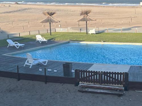 una piscina junto a una playa con sillas y sombrillas en chacrass mar azul en Balneario Mar Azul