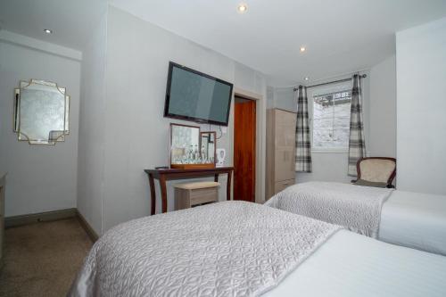 a bedroom with two beds and a flat screen tv at Redcliffe Hotel in Inverness