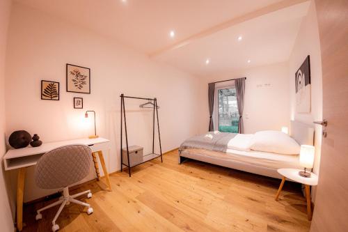 a bedroom with a bed and a desk and a chair at Servus Apartments Premium in Vilshofen an der Donau