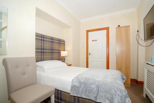 a bedroom with a bed and a chair and a television at Redcliffe Hotel in Inverness