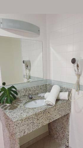 a bathroom counter with a sink and a mirror at Imperial Suítes by Prado in Petrópolis