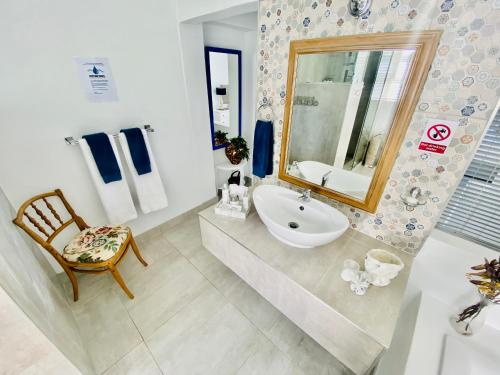 a bathroom with a sink and a mirror and a chair at My-konos in St Francis Bay