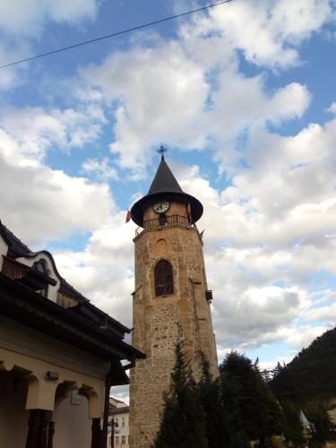 Una torre alta con un reloj en la parte superior. en Central Park Studio, en Piatra Neamţ