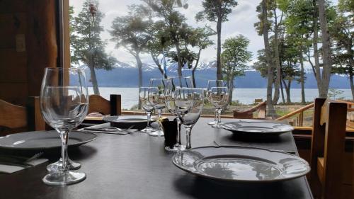 a table with wine glasses and a view of the ocean at Hostería Boutique Fuegos del Sur in Ushuaia