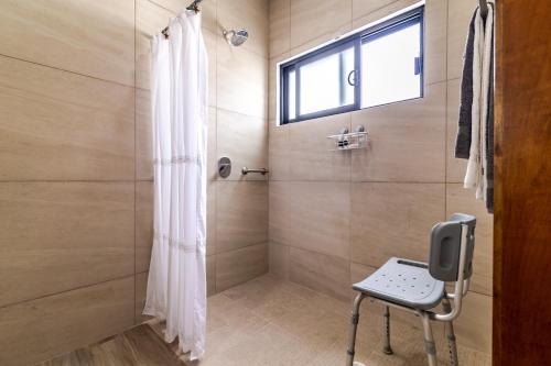 a shower with a glass door and a chair in a bathroom at Milan San Marino in Tijuana