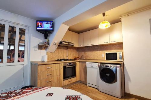 a kitchen with a stove and a tv on the wall at Casa de langa rau RUCAR in Rucăr