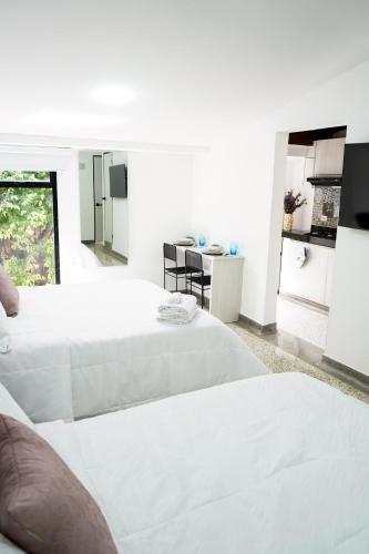 um quarto branco com 2 camas e uma cozinha em Hotel Casa Luna em Cúcuta