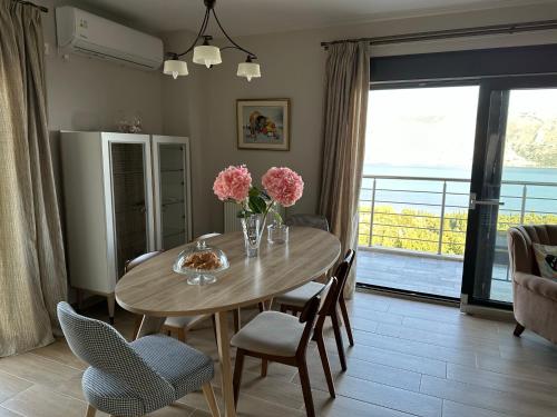 a dining room with a table with flowers and chairs at Villa Argyro in Lixouri