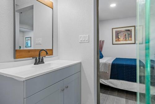 a bathroom with a sink and a mirror and a bed at South Tampa Central Location Efficiency Suite in Tampa
