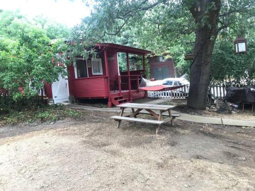 una mesa de picnic frente a una cabaña roja con un árbol en Cozy, Cheerful & Charming Cabin - Historic Julian, en Julian
